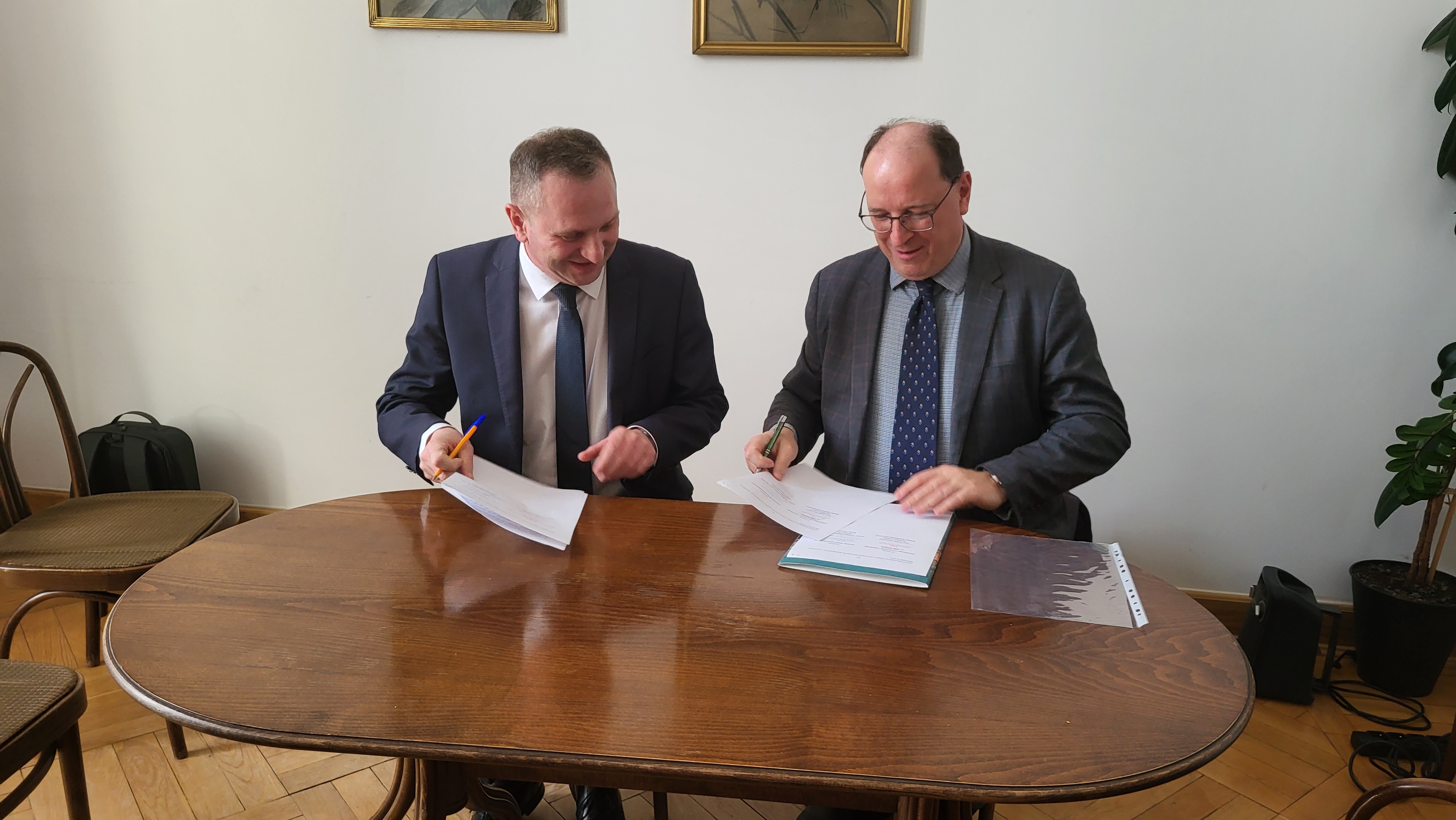 Dwóch mężczyzn - dr hab. Grzegorz Marzec i Paweł Kras - podpisuje umowę o współpracy. 